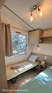 Habitación pequeña con cama y ventana en Les mobil homes de NOLY Draps inclus ,TV ,Clim, en Port-la-Nouvelle