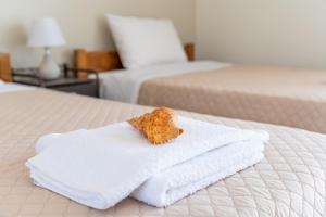 um urso de peluche sentado numa pilha de toalhas numa cama em O Molos em Marmari