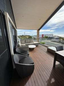a balcony with chairs and a couch on a deck at Seascape Beach House in Capel