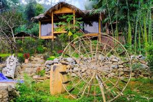 a large wooden wheel in front of a building at Homestay Toan Tra Tram Tau in Cham Ta Lao