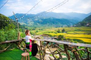 a woman standing on a wooden bridge overlooking a valley at Homestay Toan Tra Tram Tau in Cham Ta Lao