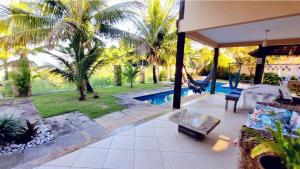 un patio con hamaca y una piscina con palmeras en Casa com vista para o Mar de Taperapuan, en Porto Seguro