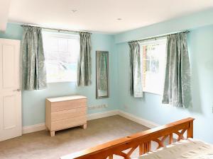 a bedroom with blue walls and two windows and a bed at Garden Cottage 1 - Uk42881 in Liphook