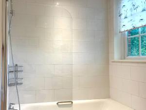 La salle de bains blanche est pourvue d'une douche et d'une baignoire. dans l'établissement Garden Cottage 1 - Uk42881, à Liphook