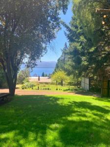 un parque con césped verde, árboles y un cuerpo de agua en Casa La Quinta - Tiny House en San Carlos de Bariloche