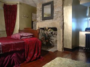 a bedroom with a fireplace and a bed with red sheets at Falstone Barns in Falstone