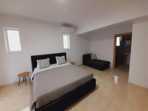 a bedroom with a large bed and a chair at Roseberry Studios in Faliraki