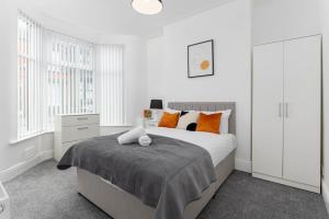 a white bedroom with a bed with orange pillows at Host Liverpool - Anfield's Comfy Corner, Stylish & Fam-Friendly in Liverpool