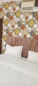 Hotel king palace في شانديغار: سرير بمخدات وجدار بورق جدران