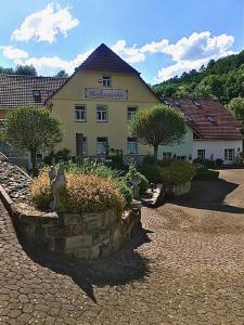 a cat sitting on a stone wall in front of a building at Pension Hühnermühle in Volkerode