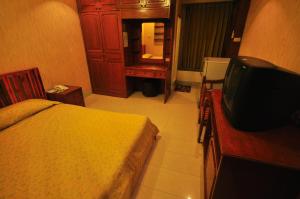 1 dormitorio con 1 cama y TV. en Sathorn Saint View Serviced Apartment, en Bangkok