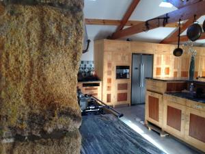 a kitchen with wooden cabinets and a large stone wall at Falstone Barns in Falstone