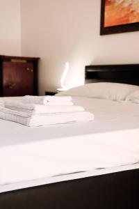 Una cama con sábanas blancas y toallas. en Delta Apartments, en Bari