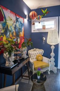 Boutique Hotel Ferrara في فيرّارا: غرفة زرقاء مع كرسي وطاولة مع زهور