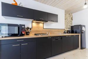 a kitchen with black cabinets and a microwave at Le grand clos, 3 étoiles in Pont-Saint-Martin