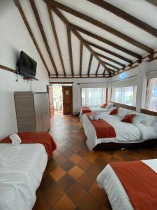 a room with three beds and a flat screen tv at Hotel Casa Campestre Villa Anita in Villa de Leyva
