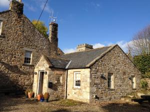 an old stone house with two chimneys on it at Falstone Barns in Falstone