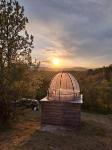 ein kleines Observatorium auf einem Feld mit Sonnenuntergang im Hintergrund in der Unterkunft Rtanj hotel sa 1000 zvezdica 2 in Vrmdža