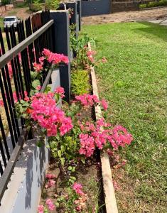 een tuin met roze bloemen naast een hek bij The GA Apartment in Abeokuta