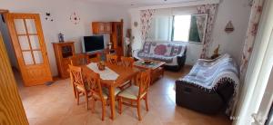 sala de estar con mesa, sillas y TV en Villa Sirena, en Cala en Blanes