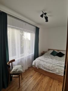 1 dormitorio con cama, ventana y silla en Zielony Zakątek Ciężkowice, en Ciężkowice