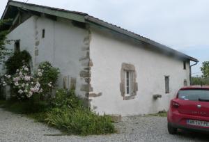 une voiture rouge garée devant un bâtiment blanc dans l'établissement Charmante maison du XVIIe siècle, à Came