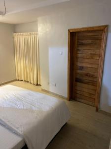 1 dormitorio con 1 cama y puerta de madera en The GA Apartment, en Abeokuta