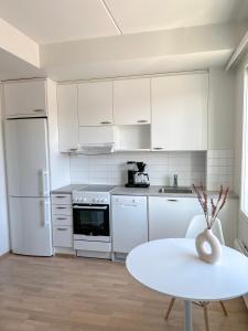 a white kitchen with a table and a white refrigerator at Studio Apartment Station in Oulu