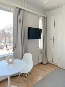 a white living room with a white table and a tv at Studio Apartment Station in Oulu