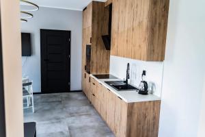 a kitchen with wooden cabinets and a black door at Apartament 101 Aquarius Boszkowo in Boszkowo