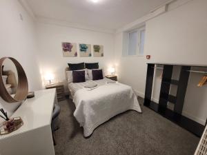 a white bedroom with a bed and a mirror at La Casa Bella in Sheffield