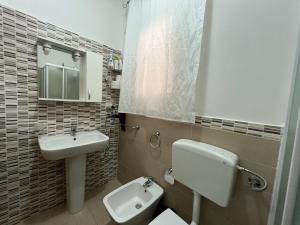 bagno con lavandino, servizi igienici e specchio di La Petite Maison ad Augusta