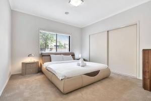 een witte slaapkamer met een groot bed en een raam bij Spacious 4BR House In Great Location in Point Cook