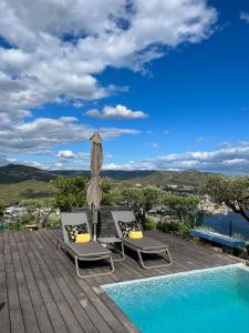 a patio with two chairs and an umbrella next to a swimming pool at Quinta Pecêga - AL in Peso da Régua