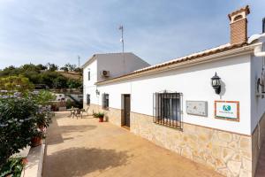 ein weißes Gebäude mit einer Steinmauer und einer Terrasse in der Unterkunft Alojamiento Rural el Viso in El Chorro