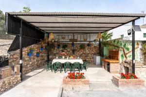 eine Terrasse mit einem Tisch, Stühlen und einer Steinmauer in der Unterkunft Alojamiento Rural el Viso in El Chorro