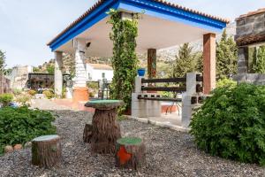 um jardim com um banco e troncos de árvores em Alojamiento Rural el Viso em El Chorro