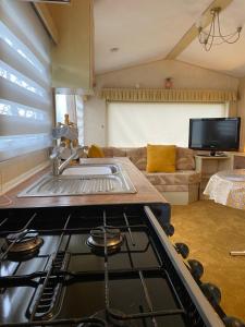 a kitchen with a stove and a living room at Annie’s Corner in Ingoldmells