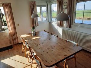a dining room with a wooden table and chairs at Vakantiehuisjes Marsherne in Poppingawier