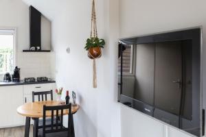 a kitchen with a table and a large television on a wall at Huisje Sasa in Hierden