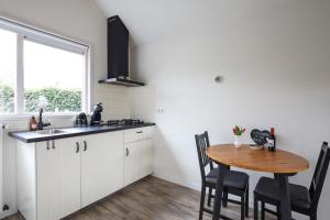 a kitchen with white cabinets and a wooden table at Huisje Sasa in Hierden