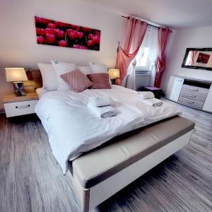 a bedroom with a large white bed with red paintings on the wall at Carpe Diem Lakeside Apartment in Szczecin