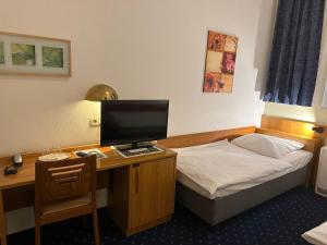 a bedroom with a desk with a bed and a computer at Centrum Hotel Commerz am Bahnhof Altona in Hamburg