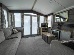 a living room with a couch and a tv at Beautiful Caravan With Decking At Naze Marine Park, Sleeps 8 Ref 17341br in Walton-on-the-Naze