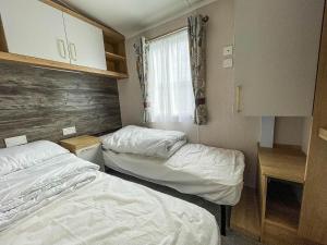 two beds in a small room with a window at Beautiful Caravan With Decking At Naze Marine Park, Sleeps 8 Ref 17341br in Walton-on-the-Naze