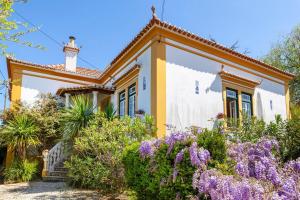 uma casa com flores em frente em B&B Quarto Violeta com Chaminé em Ramalhal