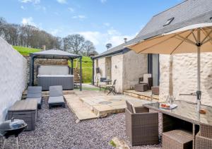a patio with a table and an umbrella at USK Barn in Llanbadoc