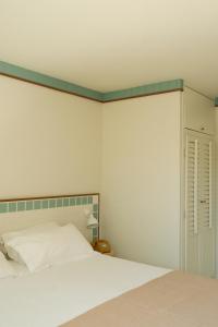 a bedroom with a white bed with a green border at Hotel des Dunes in Cap-Ferret