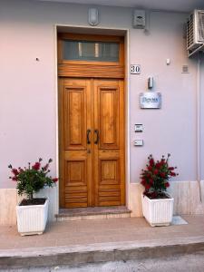 a wooden door on a building with two potted plants at "Sicilia Bedda" in Avola