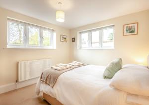 um quarto com uma grande cama branca e 2 janelas em Breaker Apartment em Southwold